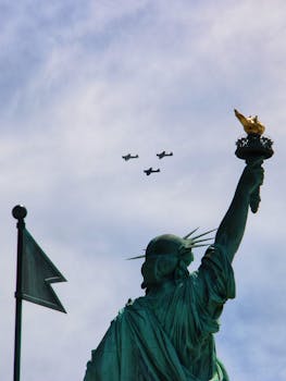 Iconic Statue of Liberty with airplanes flying above in New York, a classic city landmark view.