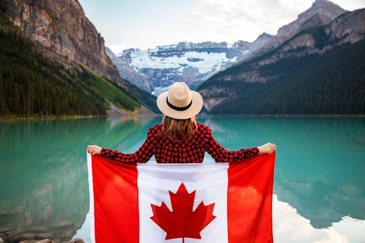 Woman holding a Canadian flag at stunning Lake Louise, Alberta, embracing nature and patriotism.